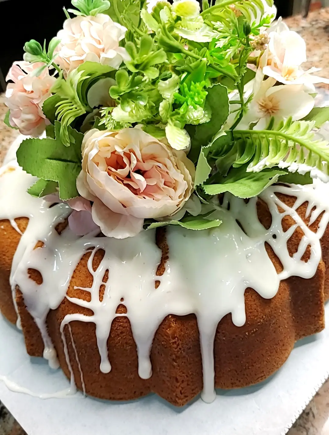 Snapchat-744302875 (1) A bundt cake with white frosting and flowers on top.